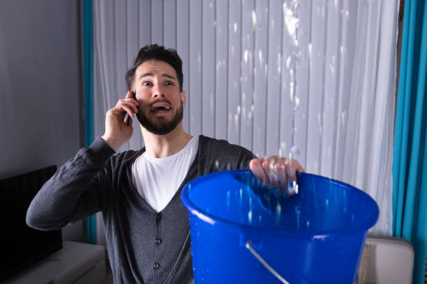 istock Man Collecting Water In Bucket While Calling Plumber 949224948