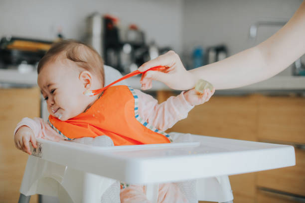 ребенок плачет во время обеда - baby eating child mother стоковые фото и изображения