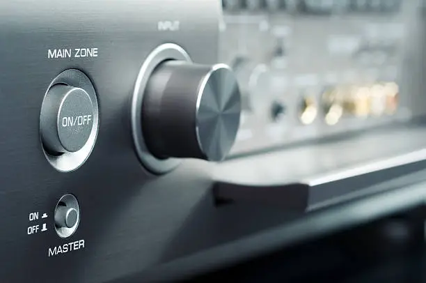 Power button and volume knob on the stereo audio video receiver. Very shallow DOF.