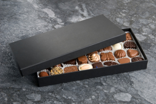 Luxury chocolate box with various white and dark chocolates on the marble.