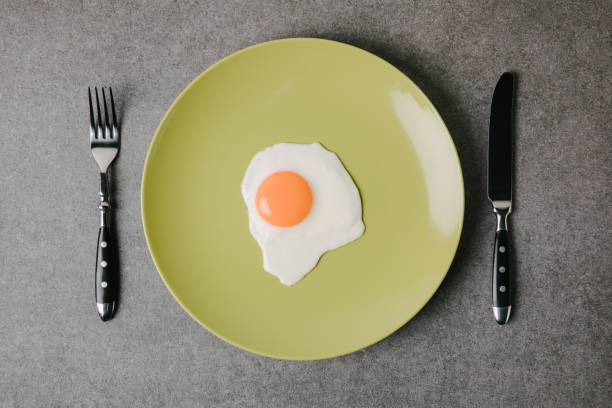 istock top view of tasty fried egg on plate and fork with knife on grey 949234816