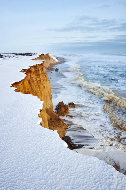 Sandy winter snowy cliff above the storm sea