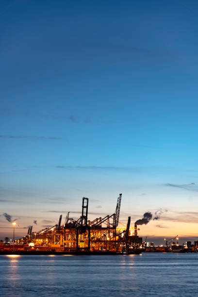 istock Sunset and gradient blue sky on the cranes loading containers at the biggest European seaport, Rotterdam, Netherlands 949253246