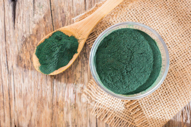 istock Spirulina powder and tablets on wooden background 949256018