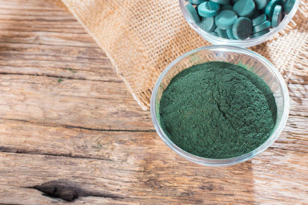 istock Spirulina powder and tablets on wooden background 949258292