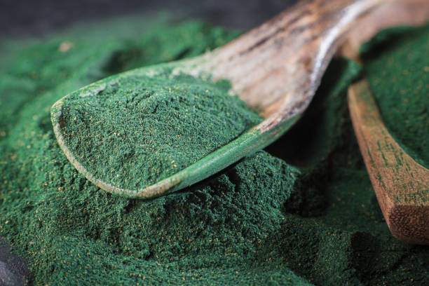 スピルリナ粉末および錠剤の木製の背景 - chlorella spirulina bacterium algae nutritional supplement ストックフォトと画像