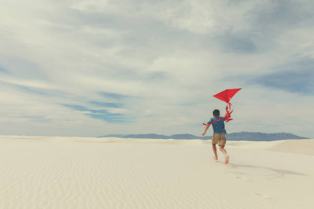 young boy runs with kite at white sands - child rear view running nature imagens e fotografias de stock