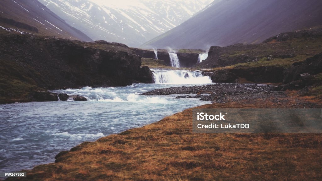 Iceland valley View of untouched Iceland nature. In background there are snow-caped mountains, and closer there are several small waterfalls who are going one after another, creating stunning view. Adventure Stock Photo