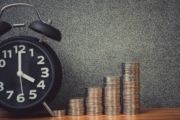 istock Alarm clock and step of coins stacks on working table, time for savings money concept. 949268952