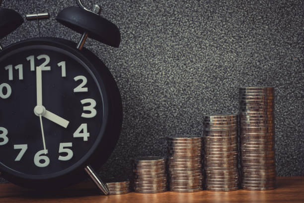 istock Alarm clock and step of coins stacks on working table, time for savings money concept. 949268956