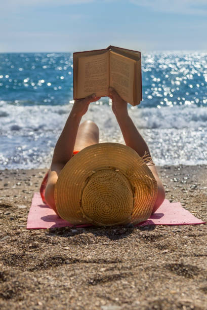 wunderschöne frau lesen am strand - book reading dress women stock-fotos und bilder