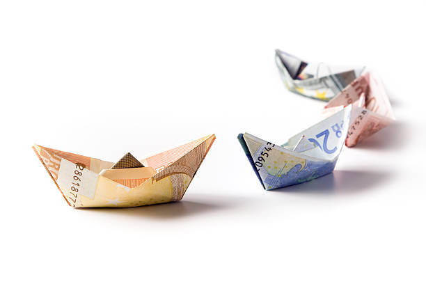 A paper boat made of paper with the image of euro banknotes of various denominations with a sail from a banknote of 500 euros on a black background