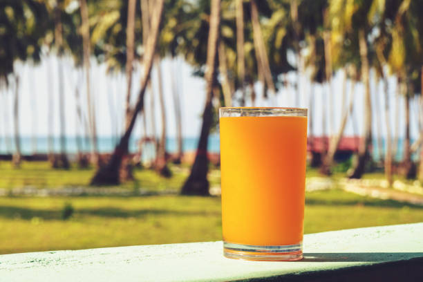 viene posto un bicchiere di succo d'arancia - beach table peach fruit foto e immagini stock