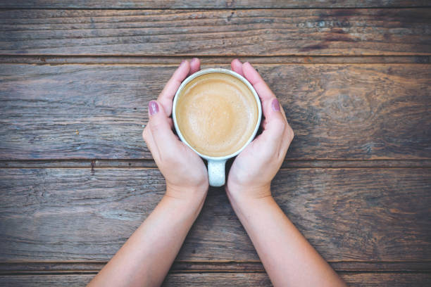 istock Top view image of woman's hands holding a cup of coffee 949306614