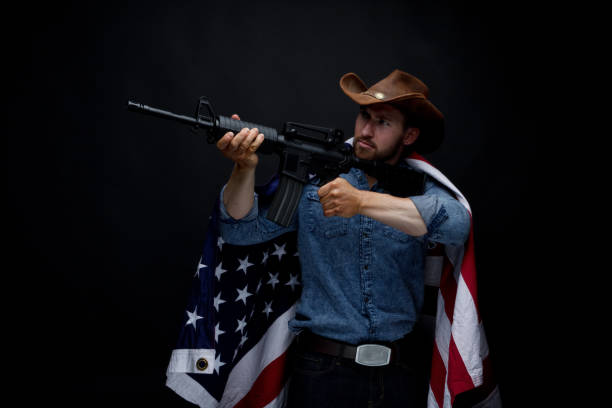 istock American man with rifle and American flag 949307094