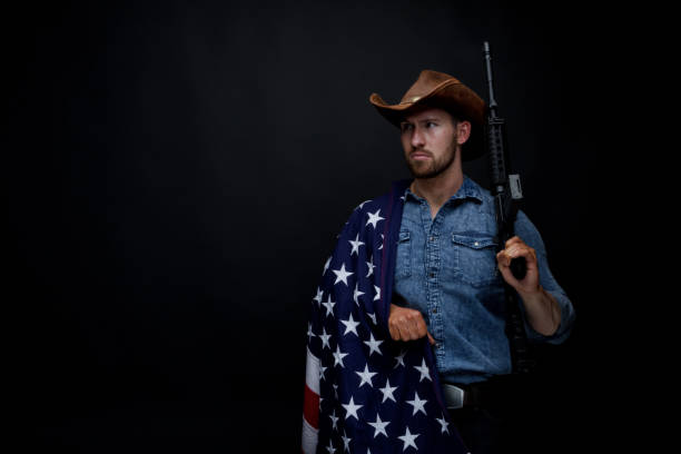 istock American man with rifle and American flag 949307234