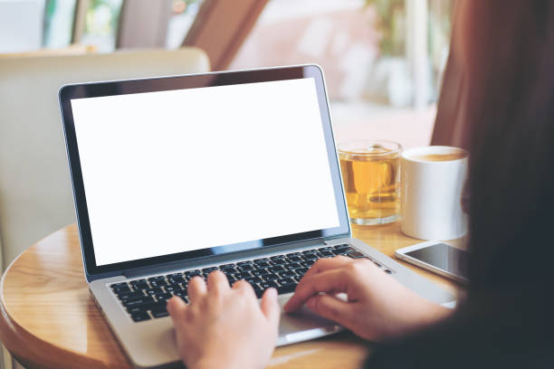 istock Mockup image of  woman's hands using laptop with blank white screen on vintage wooden table in modern loft  cafe 949307414