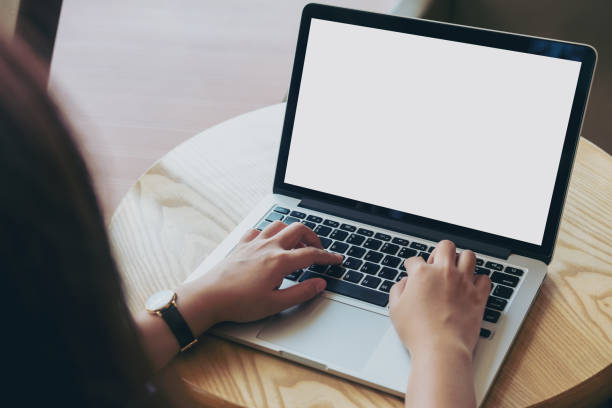 istock Mockup image of hands using laptop with blank white screen on vintage wooden table in cafe 949312502
