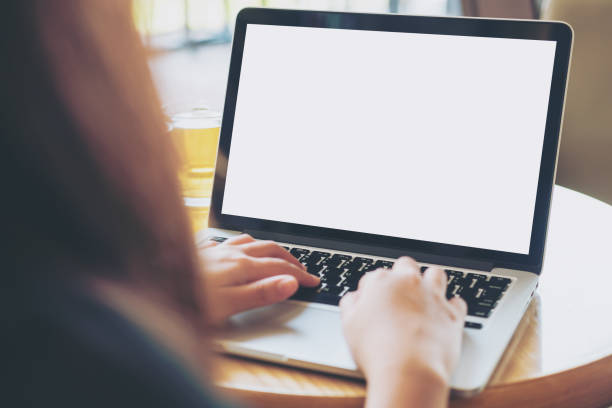 istock Mockup image of woman's hands using laptop with blank white screen on vintage wooden table in cafe 949314614