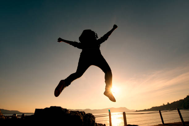 istock Hiker with backpack jumping over rocks sunrise sky on the background. 949324682