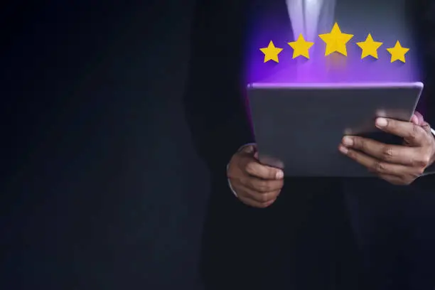 Photo of Customer Experience Concept. Part of Businessman in Black suit using digital tablet to Feedback Five Star Rating for Online Satisfaction Survey