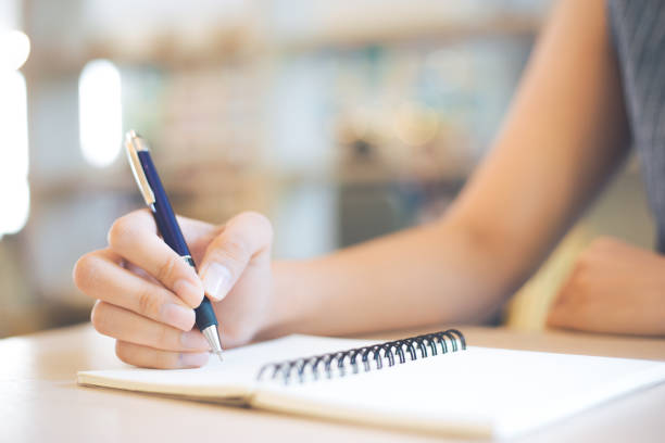 istock Business woman hand is writing on a note pad with a pen in office. 949335694
