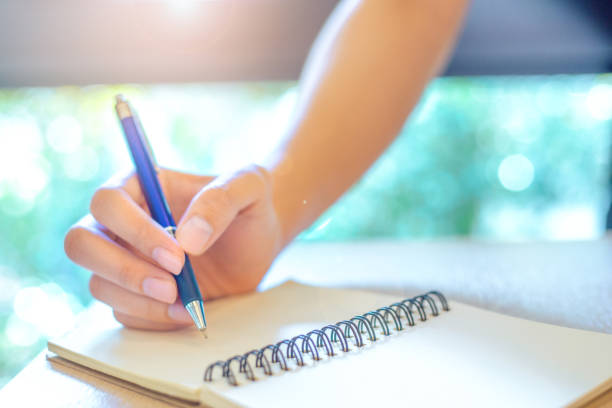 istock Business woman hand is writing on a note pad with a pen in office. 949335702