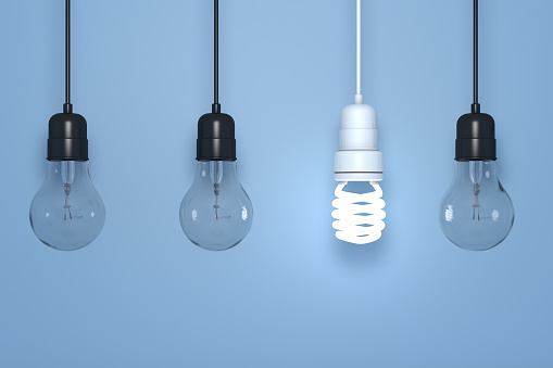 Old and Energy Efficient Light Bulbs on blue background
