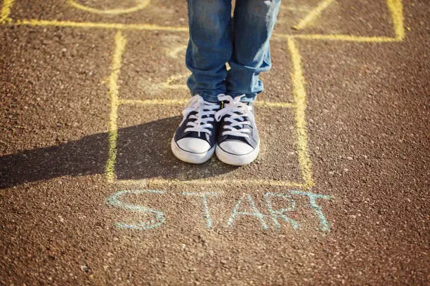 Photo of Closeup of boy's legs and playing hopscotch on playground outdoors. Hopscotch popular street game