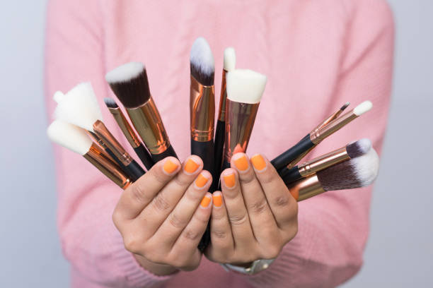 Woman holding differnt kinds of make-up brushes stock photo