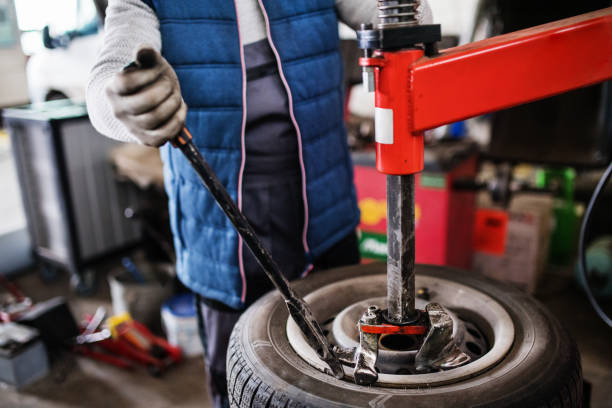 istock Man mechanic repairing a car in a garage. 949343386