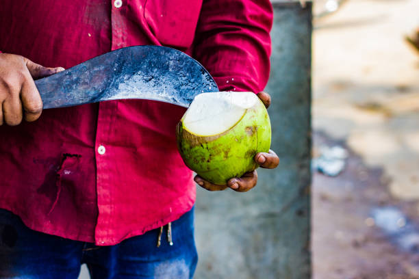istock seller cutting a raw coconut shell with sickle to take out coconut water. 949346442