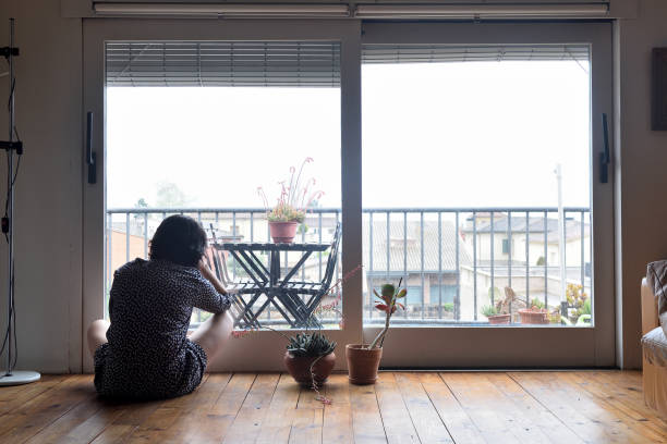 istock sad woman sitting and looking out the window 949350710