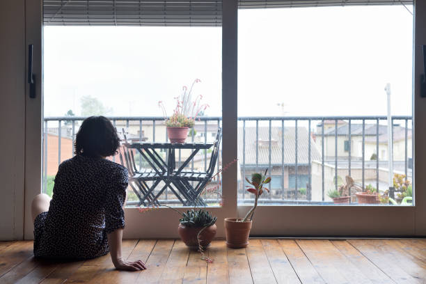 istock sad woman sitting and looking out the window 949350714