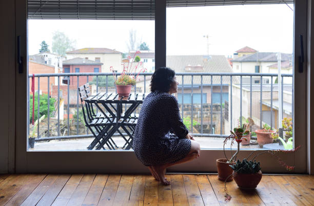 istock sad woman sitting and looking out the window 949351214