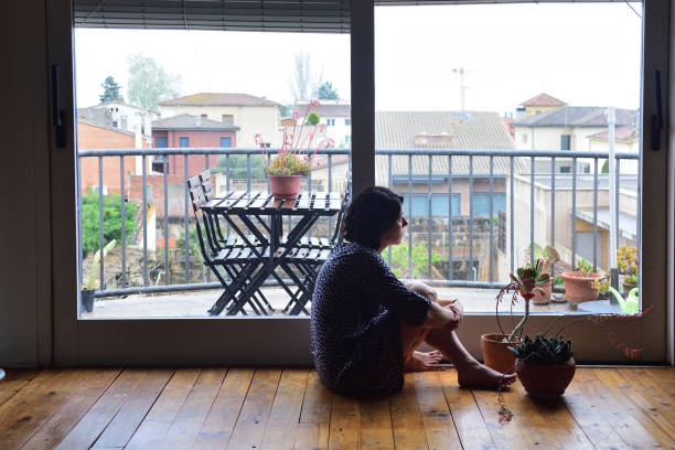 istock sad woman sitting and looking out the window 949351216