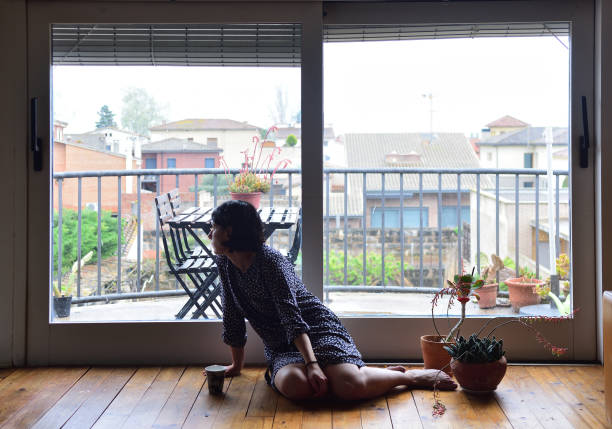 istock sad woman sitting and looking out the window 949351248