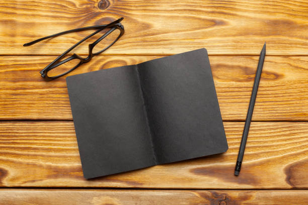 istock Mockup of black paper on wooden table 949351810