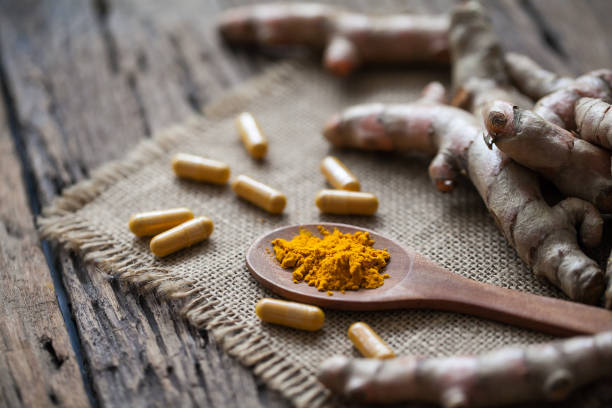 istock Turmeric powder and turmeric on wooden background 949352972