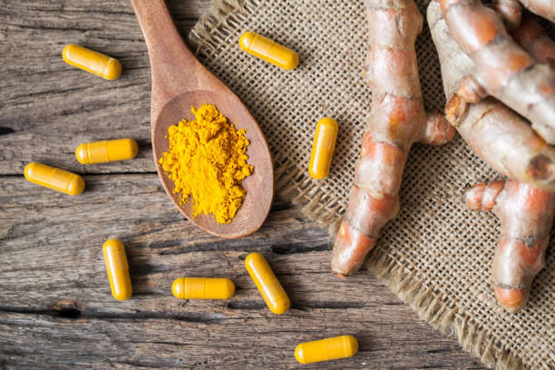 istock Turmeric powder and turmeric on wooden background 949356468