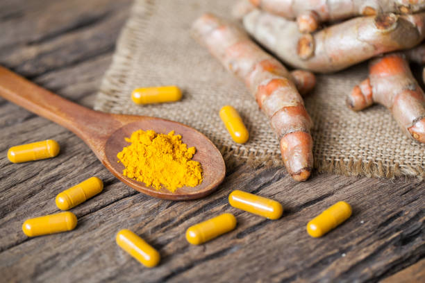 istock Turmeric powder and turmeric on wooden background 949356564