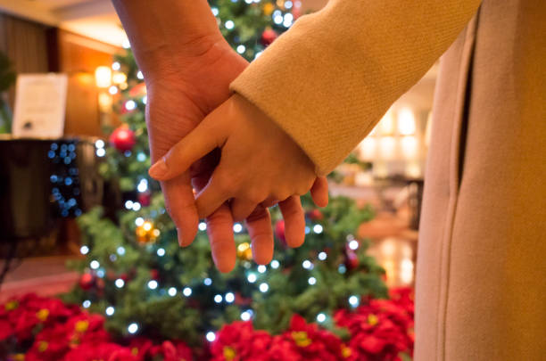istock Two couples holding hands in front of Christmas tree 949360976