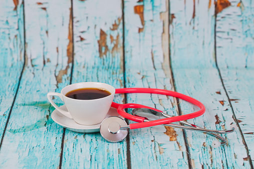 hot coffee cup with stethoscope on wood table.