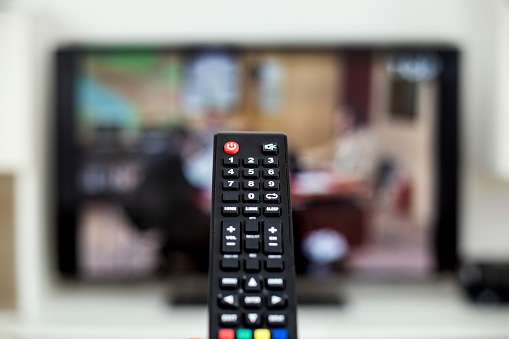 Remote control changing channels on a television broadcast.