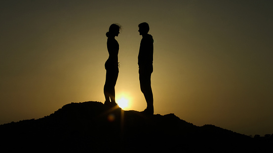 Couple on top of hill against sunset, fateful meeting on edge of earth, love
