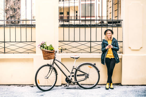istock Young woman with bicycle and smartphone in sunny spring town. 949370182