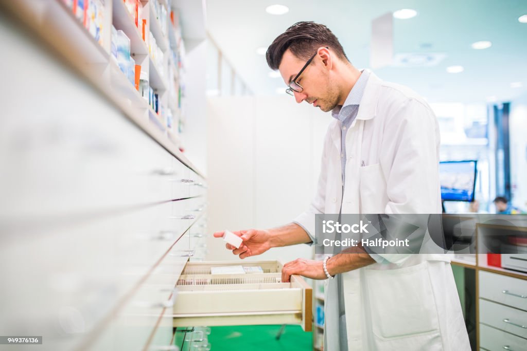 Portrait of a young friendly male pharmacist. Portrait of a young atrractive friendly male pharmacist, working. Pharmacy Stock Photo