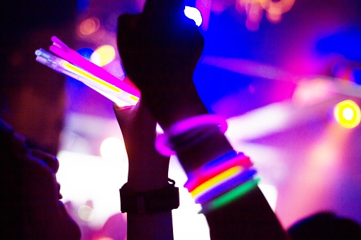 Side view of people enjoying music concert at a nightclub.
They are having fun with taking picture with mobile phone.