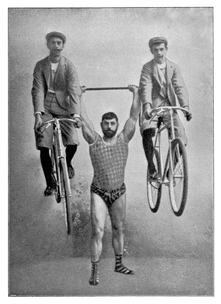 starker mann heben mann auf dem fahrrad über seinem kopf - circus strongman men muscular build stock-grafiken, -clipart, -cartoons und -symbole