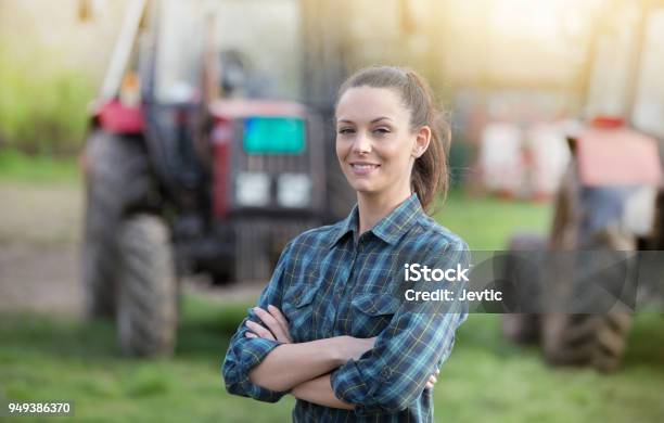 Mujer Del Granjero Frente A Tractores Foto de stock y más banco de imágenes de Agricultor - Agricultor, Adulto joven, Una sola mujer